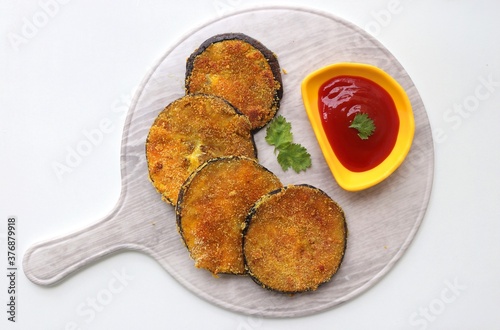 Indian side dish or appetizer  Vangyache Kaap, fried Eggplants, Crispy brinjal fry, Aubergine disks, served with tomato ketchup. With copy space photo