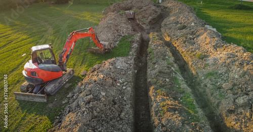 Aerial drone view of geothermal heating collector pit or trench in the ground. Excavation of ditch or holes for thermal heat exchanger for a house. Excavator on work