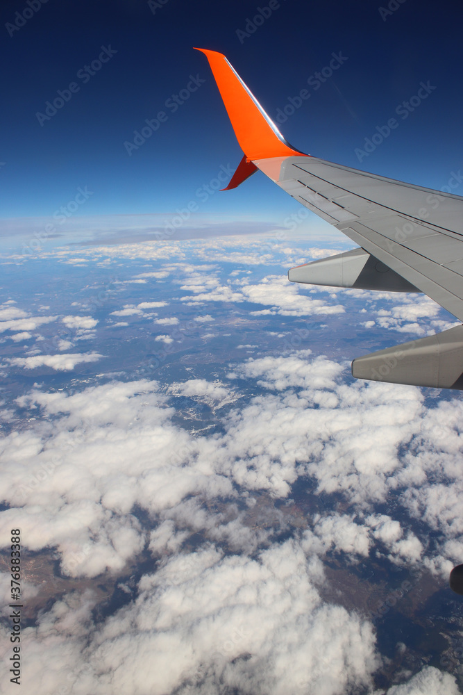Photo from the plane window. White clouds and rocky mountains. From high. Under the wing of an airplane Photo from the plane window. White clouds and rocky mountains. From high. Under the wing of an airplane