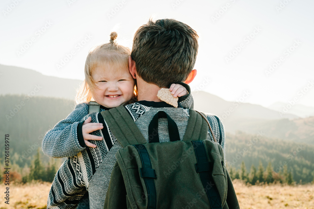 The daughter hug father on nature. Dad with backpack and child walk in the autumn. Family spending time together in mountain on vacation. Holiday trip concept. World Tourism Day. back view. The daughter hug father on nature. Dad with backpack and child walk in the autumn. Family spending time together in mountain on vacation. Holiday trip concept. World Tourism Day. back view.