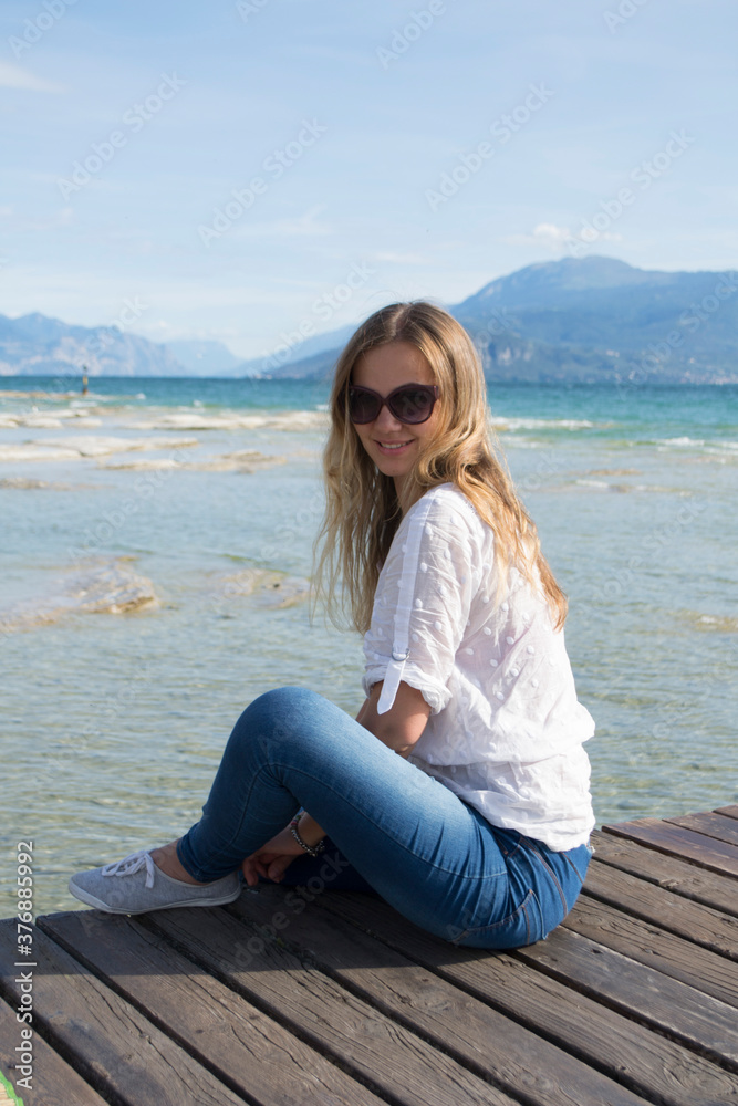 girl with blond hair in glasses resting on Lake Garda in Italy