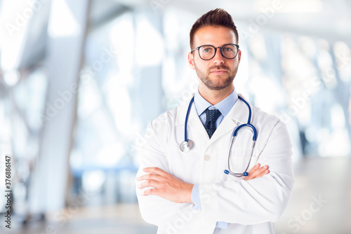 Male doctor portrait looking at camera and smiling while standing in the hospital