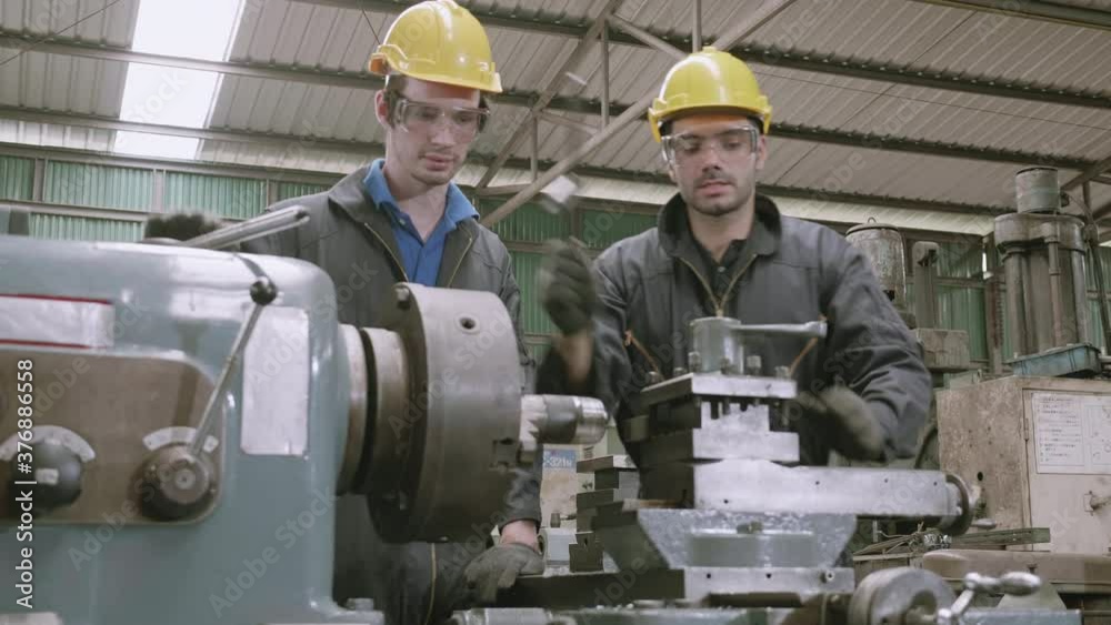 Engineer man training with foreman for apprentice using lathe, apprenticeship teaching with worker, technician and learning, inspector and labor, internship and workshop, industrial concept. Engineer man training with foreman for apprentice using lathe, apprenticeship teaching with worker, technician and learning, inspector and labor, internship and workshop, industrial concept.