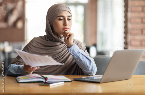 Canvas Print Pensive muslim woman manager working while sitting at cafe
