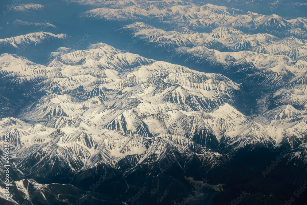 Fototapeta premium View from airplane on Earth surface - snow-capped mountains.