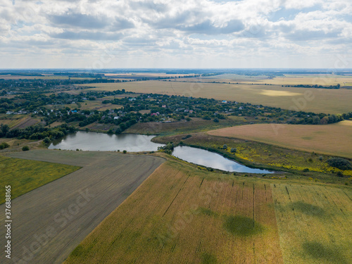 Aerial drone view. Country lake among agricultural fields.