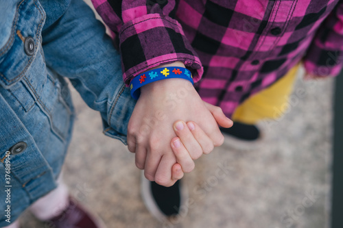 Obraz na płótnie child holds the child's hand with an autistic bracelet. Autism syndrome. World autism awareness day concept. w salonie