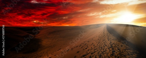 Night in the desert sand dunes. Desert against a dramatic red sky photo