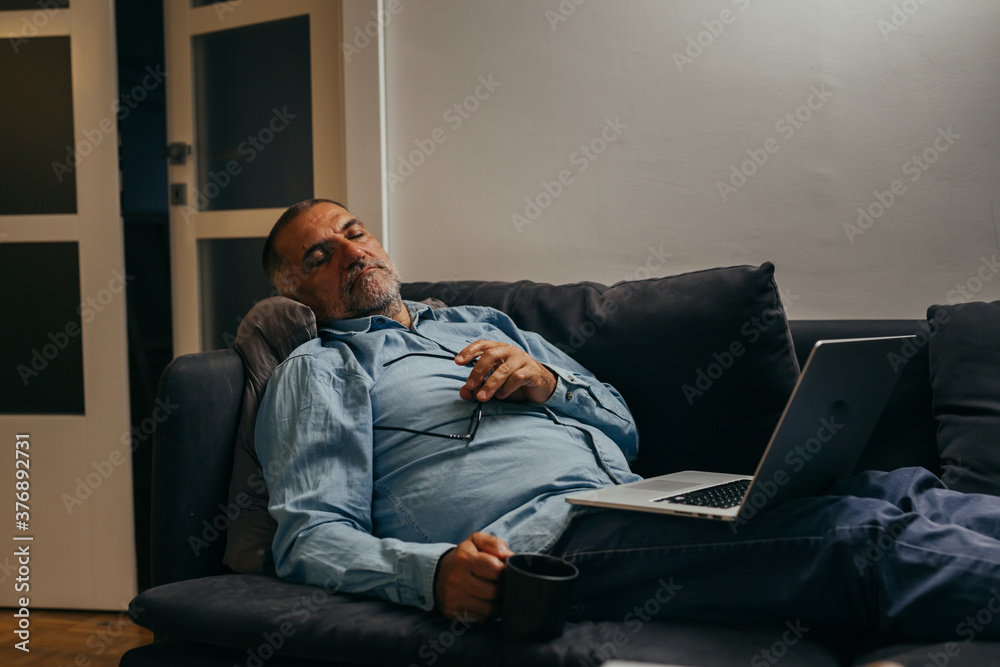 middle aged man sitting sofa and resting using laptop computer at home middle aged man sitting sofa and resting using laptop computer at home