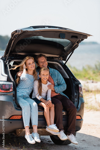 Family with daughter sitting in car trunk during vacation © LIGHTFIELD STUDIOS