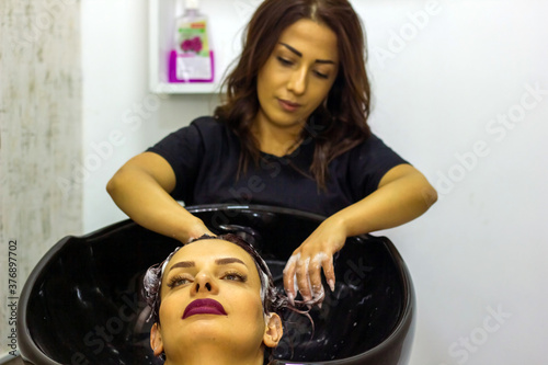 young woman washes his head in a hairdresser salon