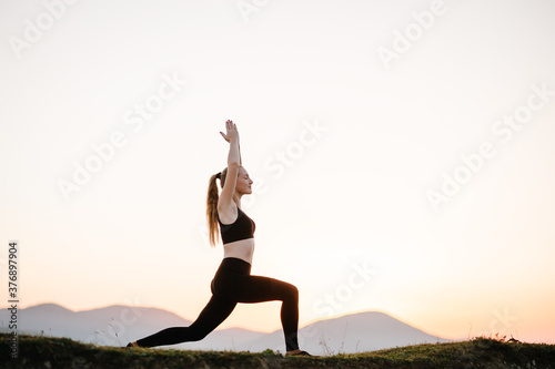 Meditation. Woman balanced, practicing meditation and zen energy yoga in mountains. Girl doing fitness exercise sport outdoors in morning. Healthy lifestyle concept. Sunrise. Side view.
