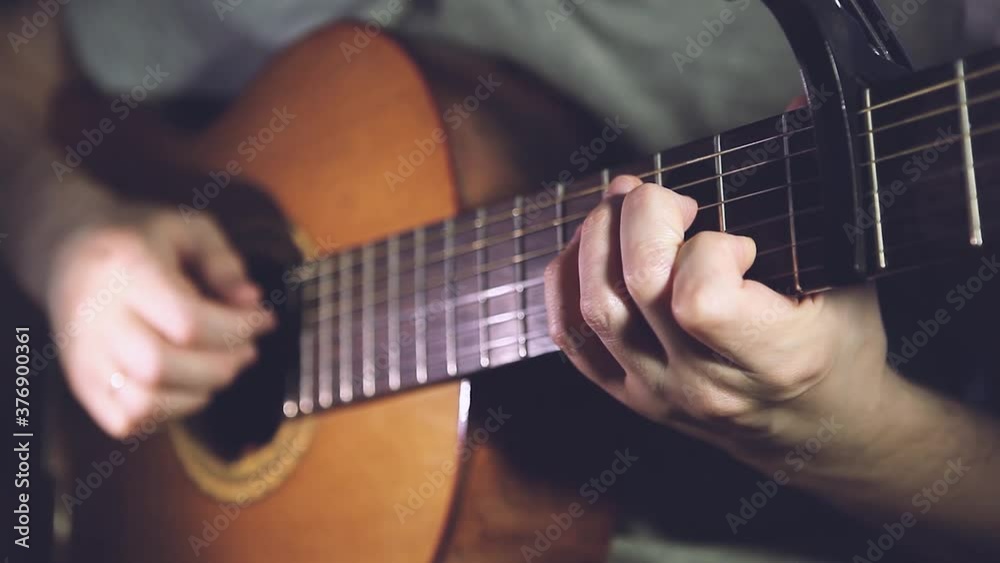 Guitar player man on a dark romantic background with lights and bokeh. Close-up fingerstyle technique Guitar player man on a dark romantic background with lights and bokeh. Close-up fingerstyle technique