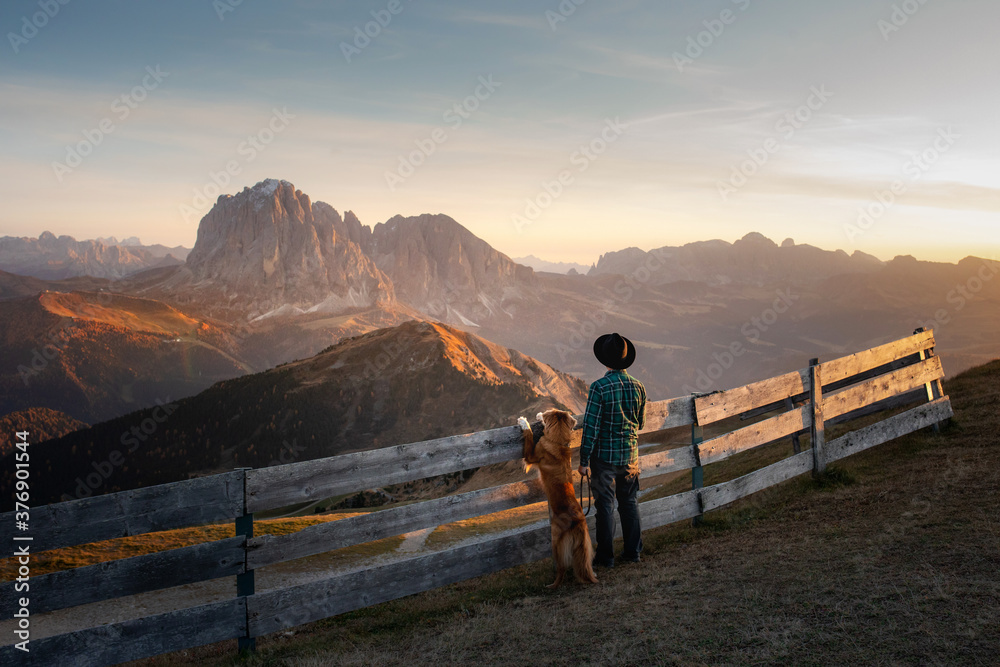 a man with a red dog looking at the mountains. Dolomites Alps. hiking, relax. Nova Scotia Duck Tolling Retriever