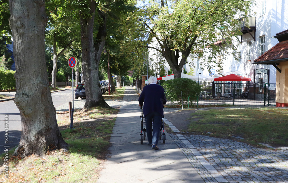 Eine Rentnerin geht mit einem Rollator spazieren.
