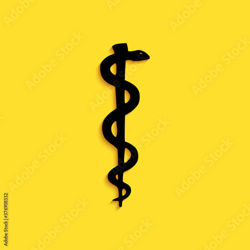 Black Rod of asclepius snake coiled up silhouette icon isolated on yellow background. Emblem for drugstore or medicine, pharmacy snake symbol. Long shadow style. Vector. photo