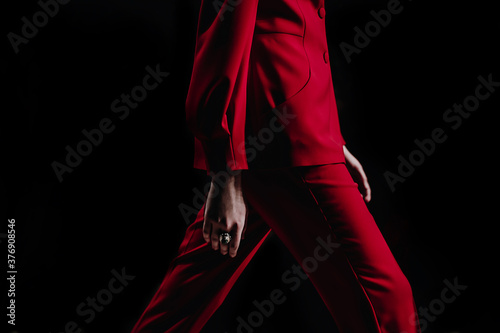 Cropped female fashion model in red stylish classy suit jacket and pants walking runway on the Fashion Show. Close up designer fashion details. Catwalk Fashion Week photo