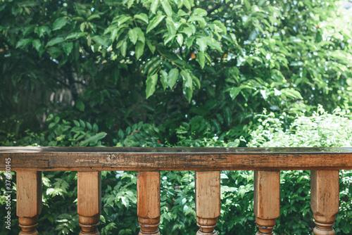 Wooden railing on porch overlooking green garden