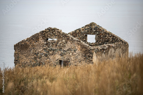 an old house stands in a field by the sea