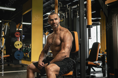 Handsome and muscular bodybuilder in a gym during workout