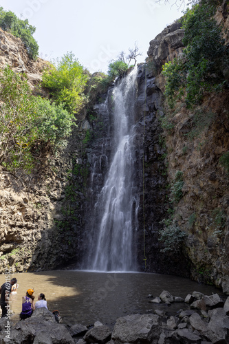 The waterfall Jalaboun  on the shallow mountain Jalaboun stream with crystal clear water and shores overgrown with trees and grass  flows in the Golan Heights in northern Israel