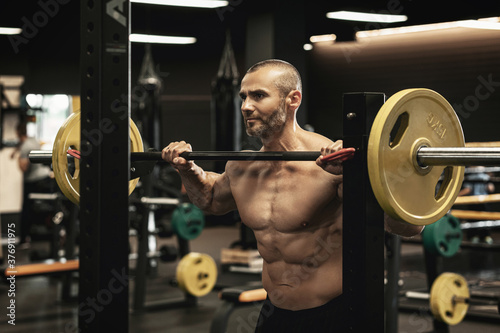 Bodybuilder during his workout with a barbell in the gym