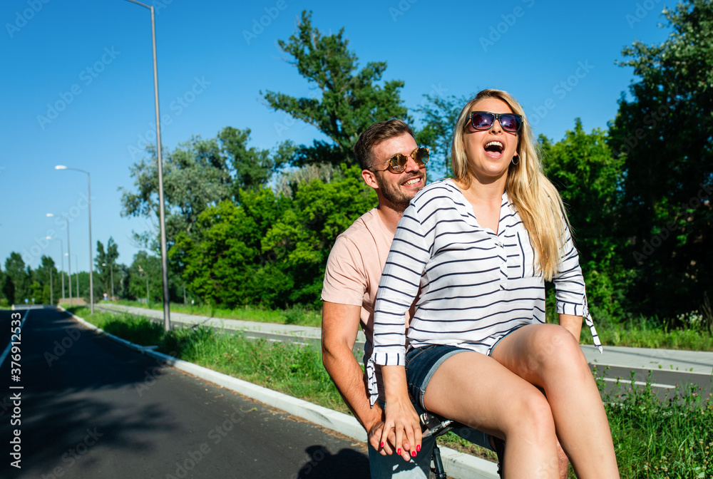 Obraz premium Cheerful young couple having fun riding on bicycle on summer day.