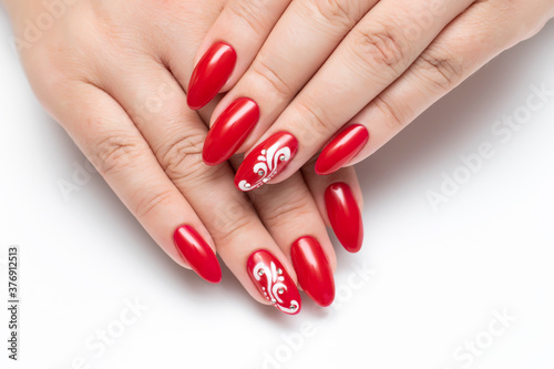 Gel nails. Red manicure on sharp long nails close-up on a white background. White monograms and crystals.