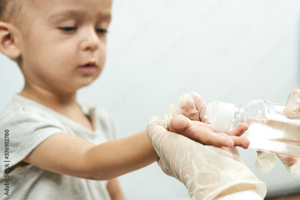 Doctor putting hand sanitizer to baby hands. Teaching a baby boy hand