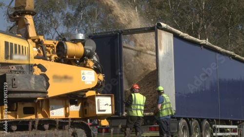 Industrial logging with a huge chipper recycling the wood chip waste photo