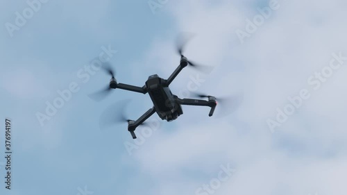 Drone Hangs in the Air against the Blue Sky, View from Below. Slow Motion photo