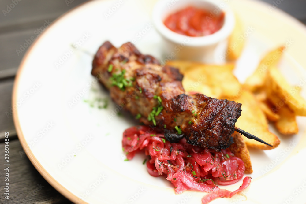 On plate there is kebab potato salad and there is ketchup next to it. Lunch menu concept On plate there is kebab potato salad and there is ketchup next to it. Lunch menu concept