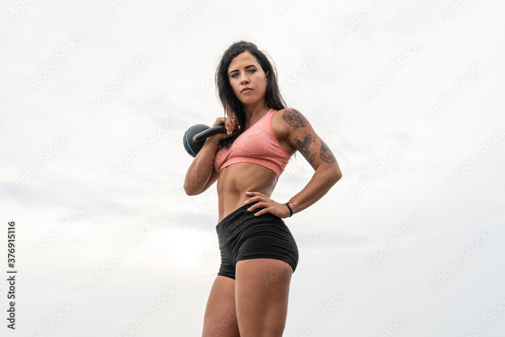 Athletic woman exercising with kettle bell. Muscular woman working out outdoors. Athletic woman exercising with kettle bell. Muscular woman working out outdoors.