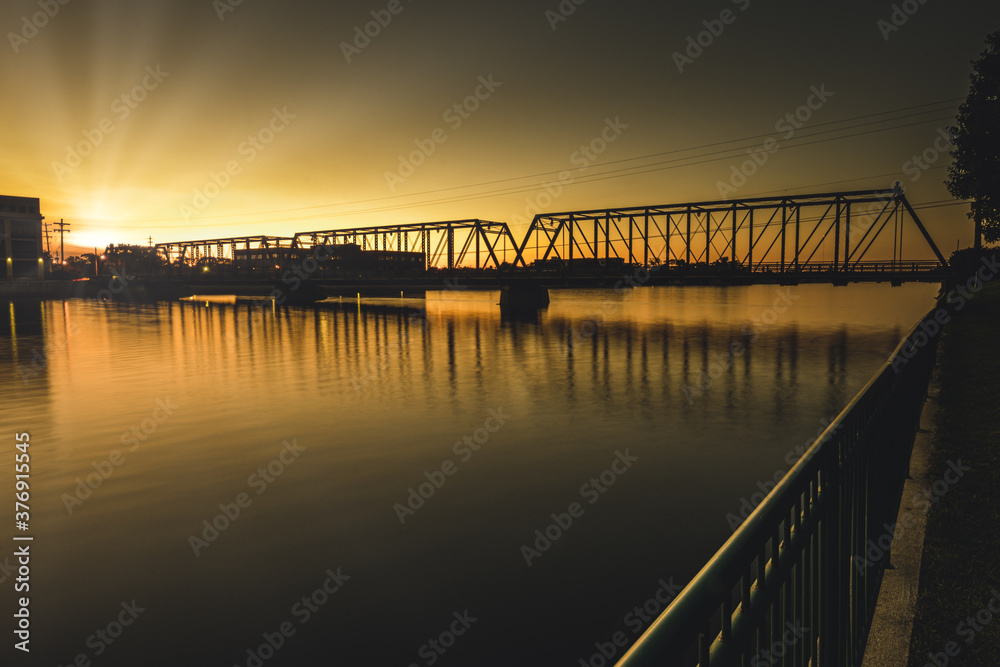 sun is setting behind the bridge ahead in the golden hour