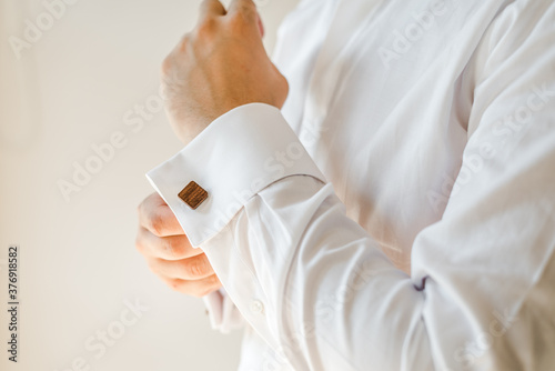 Man putting on a white shirt and cufflinks. Preparation. Formal wear. 