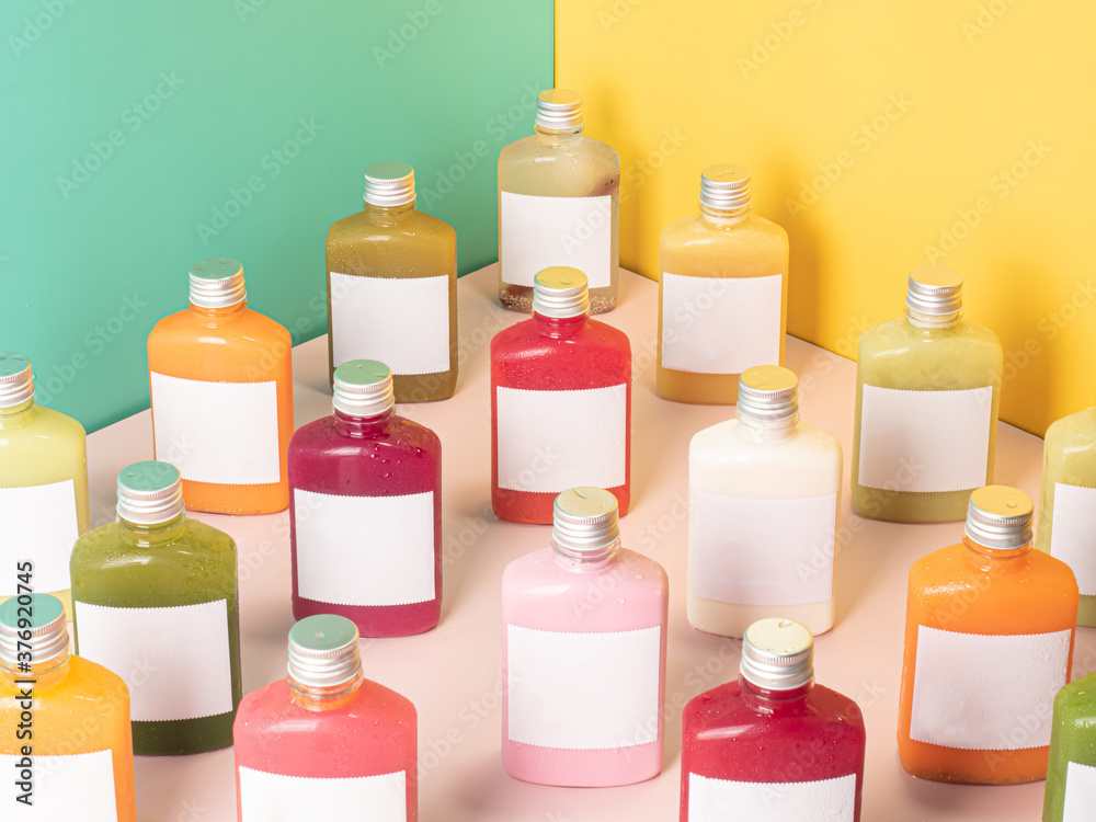 many pastel color drink in plastic bottle container with empty logo label. mixed many vegetables and fruits smoothie juice on studio colorful background.