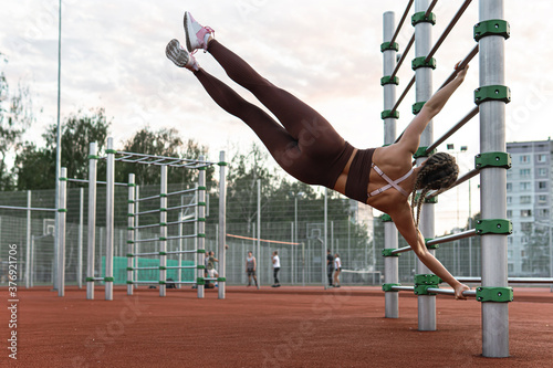 Strong woman is doing human flag exercise during her calisthenics workout photo