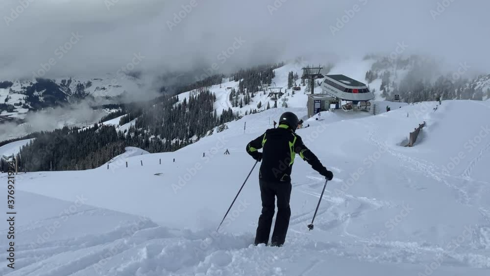 A Skier Skiing On The Downhill And Leaving A Track On The White Snow - Ski Resort In Austria During Winter. - wide shot A Skier Skiing On The Downhill And Leaving A Track On The White Snow - Ski Resort In Austria During Winter. - wide shot