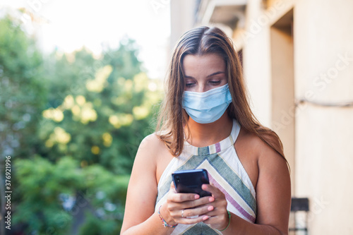 Beautiful woman wearing protective mask using a smart phone © CarlosGutierrez