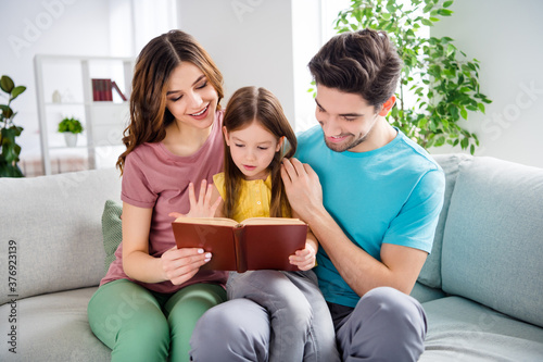 Photo of idyllic three people sit couch mother father look little girl kid read book in house indoors