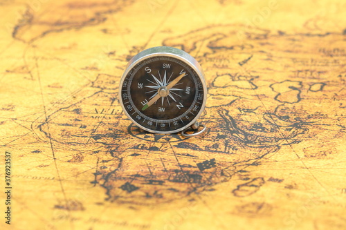 Classic round compass on background of old vintage map of world as symbol of tourism with compass, travel with compass and outdoor activities with compass © yarbeer