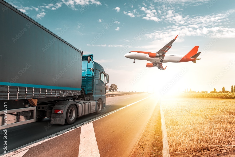 The plane is landing flying over the road with a truck