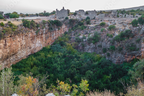 Panoramic view onto ruins of buildings, standing near edge of karst sinkhole in ancient city Kanli Divane or Canytelis, Ayaş, Turkey. There are remains of churches & tower. Photo taken in evening photo