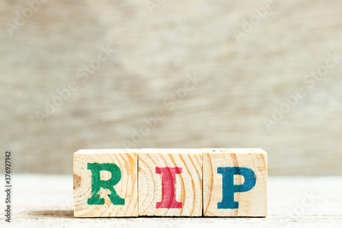 Alphabet letter in word RIP (abbreviation of rest in peace) on wood background photo