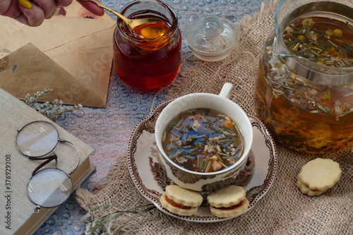 Cozy morning at home - romantic letters and old book for reading, delicious herbal tea with ginger, fresh vanilice cakes and forest honey photo