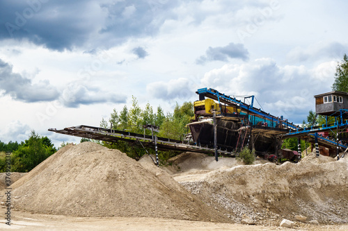 Stone crusher equipment & conveyor in industrial quarry with open-pit mining