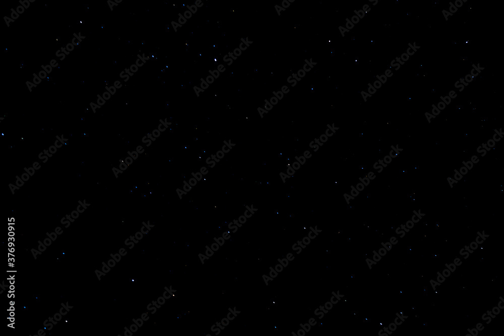 Night sky with glowing shining stars of white and blue on a black background in abundance. Wallpaper or background for banner or astrological magazine.