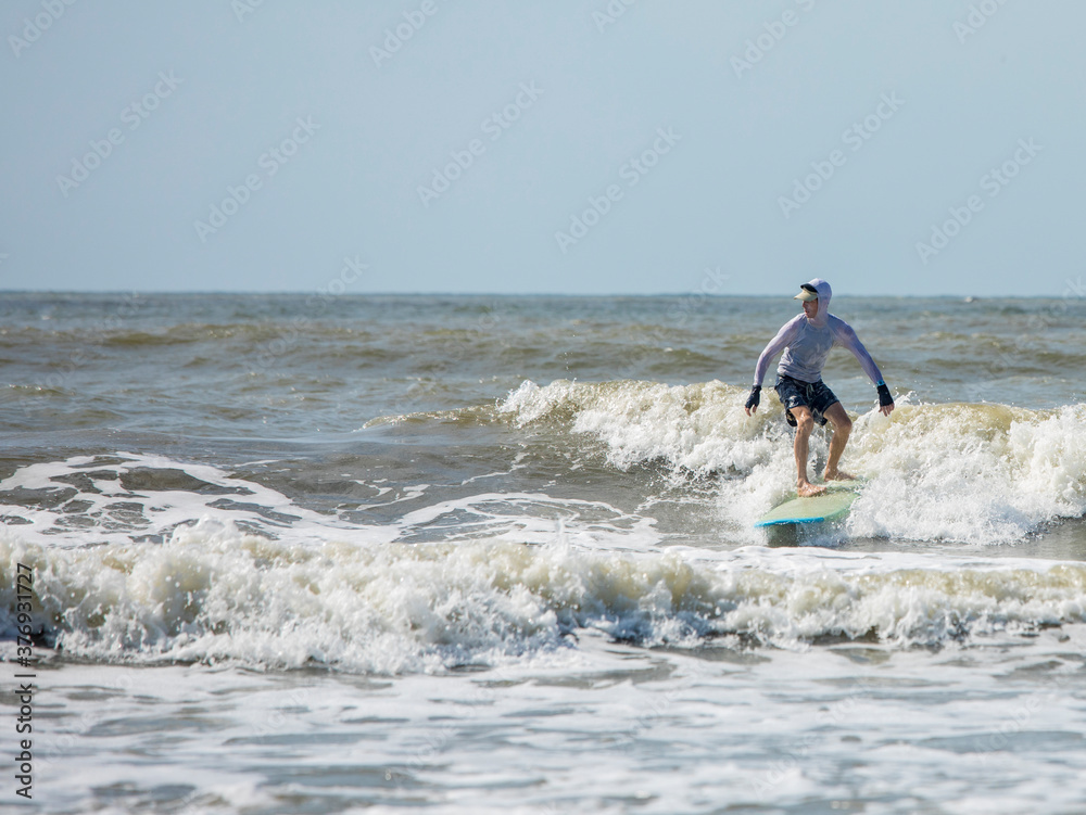 Middle aged man surfing a long board on the Atlatic Ocean in South Carolina.