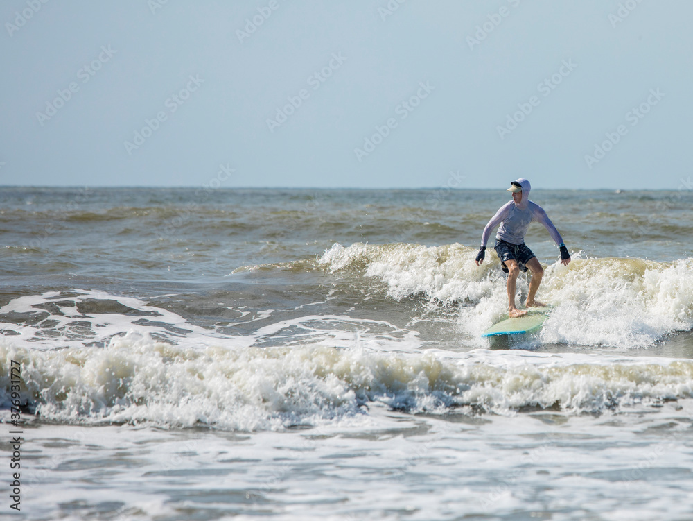 Middle aged man surfing a long board on the Atlatic Ocean in South Carolina. Middle aged man surfing a long board on the Atlatic Ocean in South Carolina.