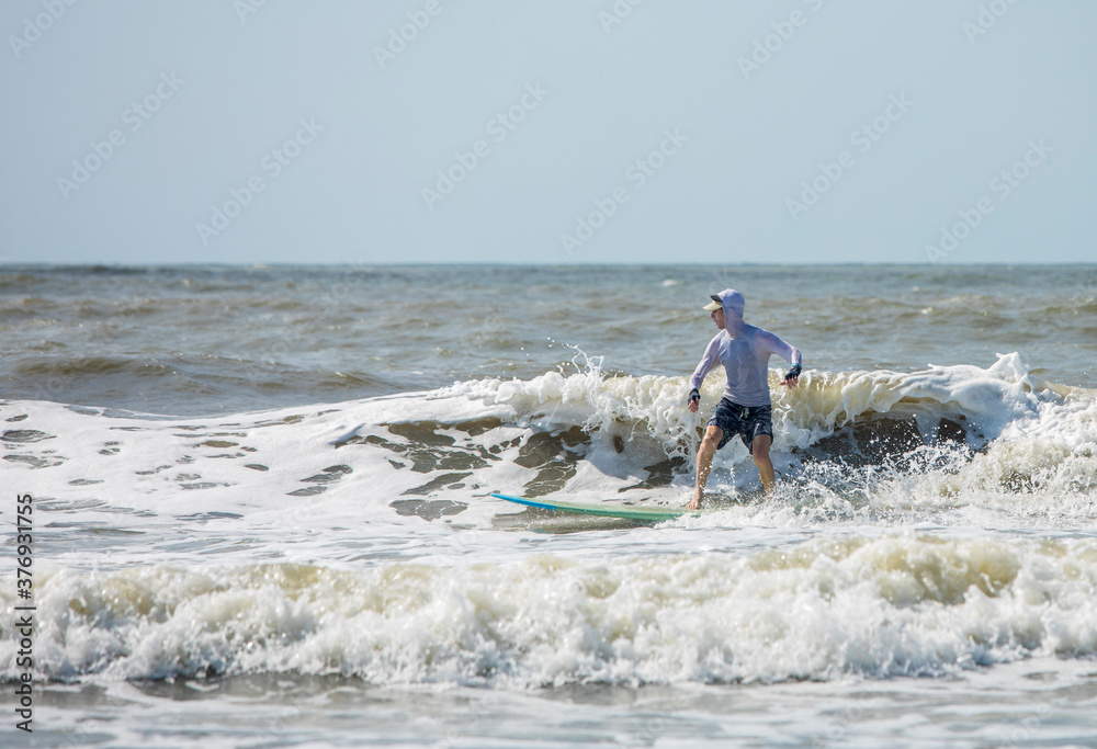 Middle aged man surfing a long board on the Atlatic Ocean in South Carolina. Middle aged man surfing a long board on the Atlatic Ocean in South Carolina.